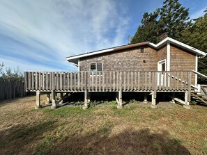 Une terrasse en bois attenante à une maison, avec une petite fenêtre et une porte.