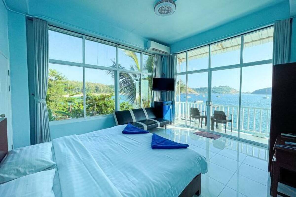 Une chambre avec un lit, une télévision et un balcon donnant sur la mer.
