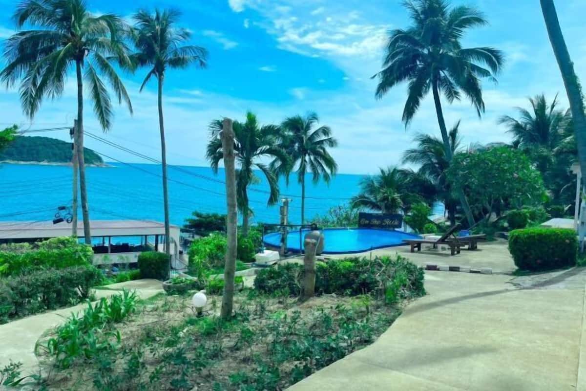 Un complexe hôtelier doté de palmiers, d’une piscine et offrant une vue sur l’océan.