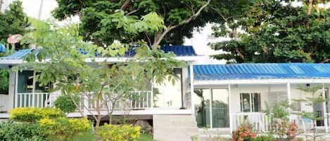 A house with a blue roof, a covered porch, and a well-maintained garden.