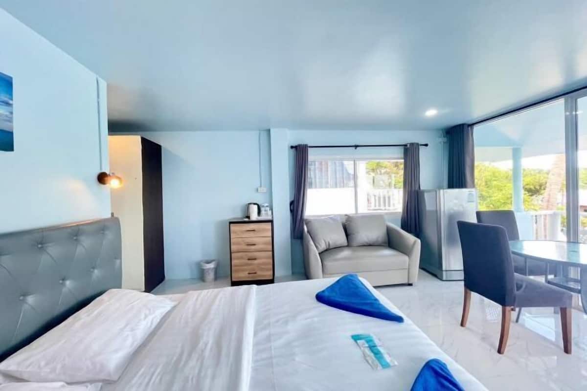Une chambre d’hôtel moderne, équipée d’un lit, d’un petit bureau, d’une chaise et offrant une vue sur l’extérieur.