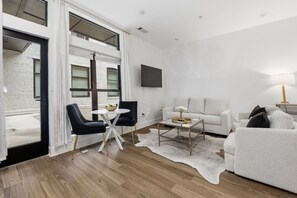 A modern living room with a sofa, two armchairs, a coffee table, and a television mounted on the wall.
