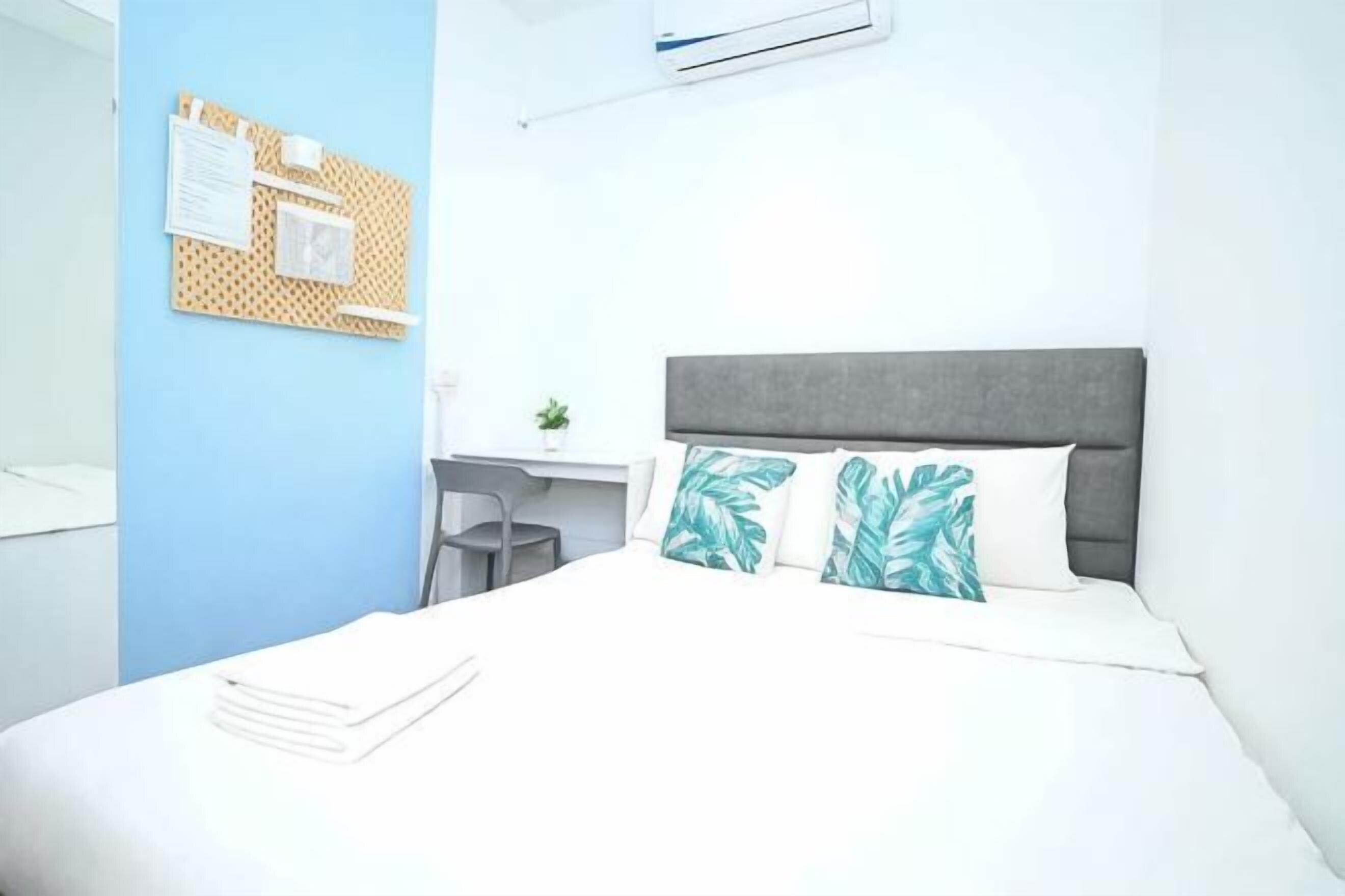 A bedroom with a bed, a desk, and a wall-mounted air conditioning unit.