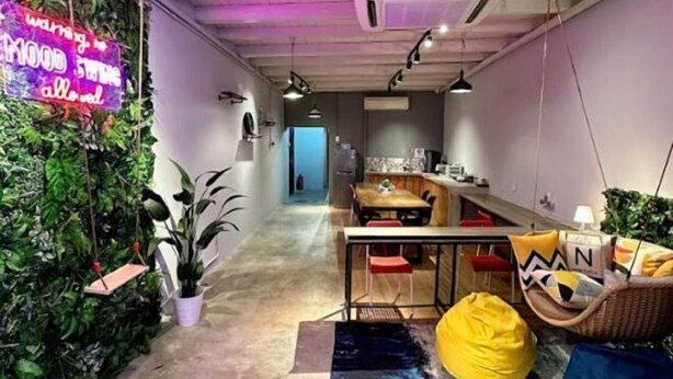 Un intérieur moderne comprenant un espace cuisine, une table à manger et un coin salon avec un fauteuil en forme de sac de haricots jaune.