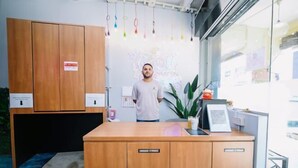 Un comptoir d’accueil avec des armoires de rangement, un panneau lumineux et une plante.