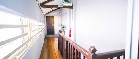 A corridor with a wooden floor, white walls, and a wooden railing.