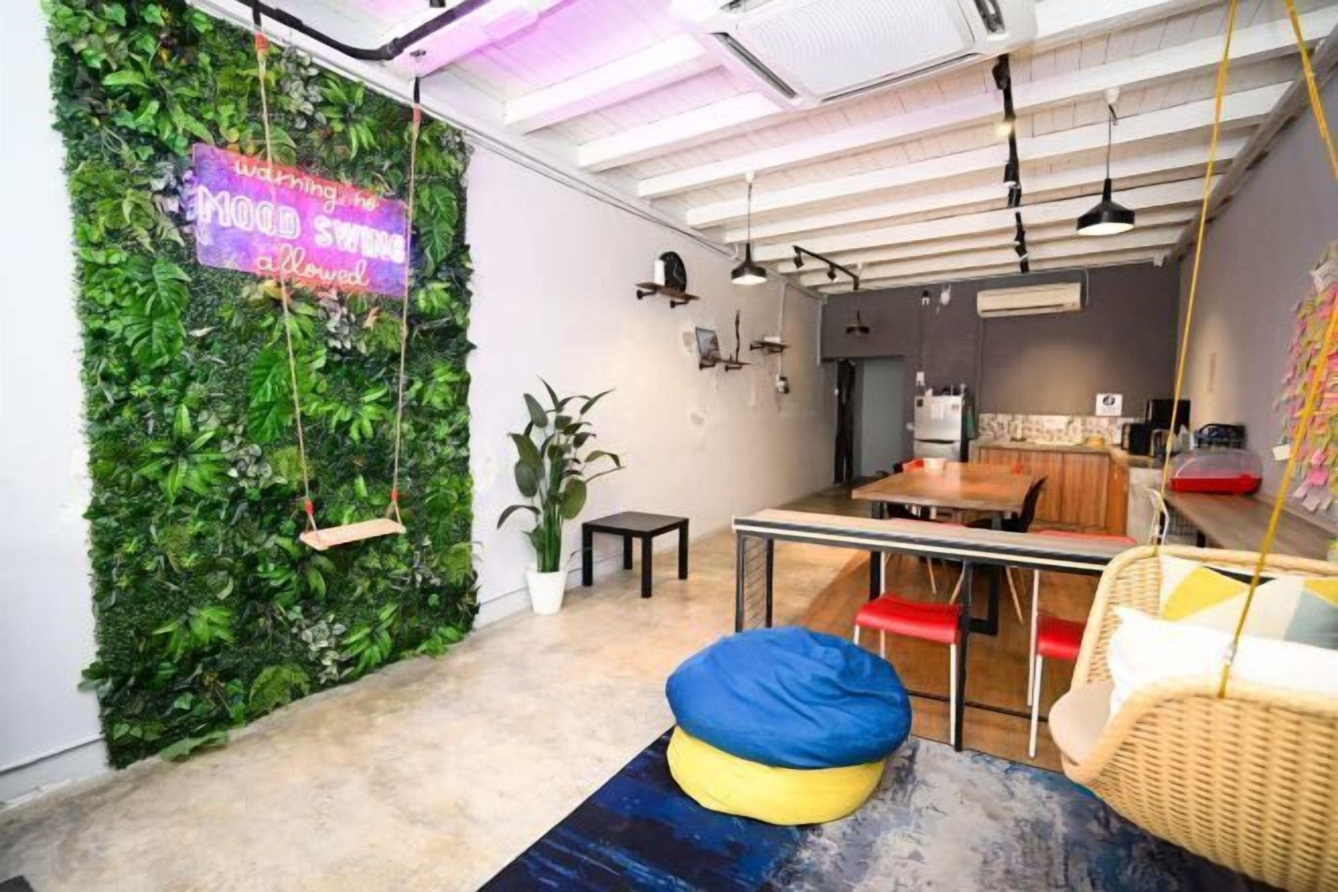 A modern interior with a green wall, swing seats, a dining area, and a hanging light fixture.