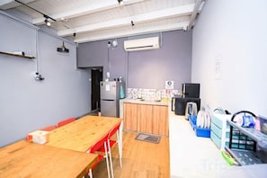 A modern kitchen with a wooden table and chairs, a refrigerator, and a microwave. - Swing & Pillows @ Beach Street (Northeast Penang Island)