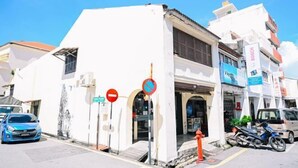 Un bâtiment blanc avec une devanture de magasin, une voiture bleue garée devant et une moto sur le côté droit.