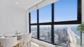 A modern room with a large window overlooking a cityscape and beach. - Cozy 2 Bedroom 2 Bathroom Ocean View Unit - Q Stay (Surfers Paradise)