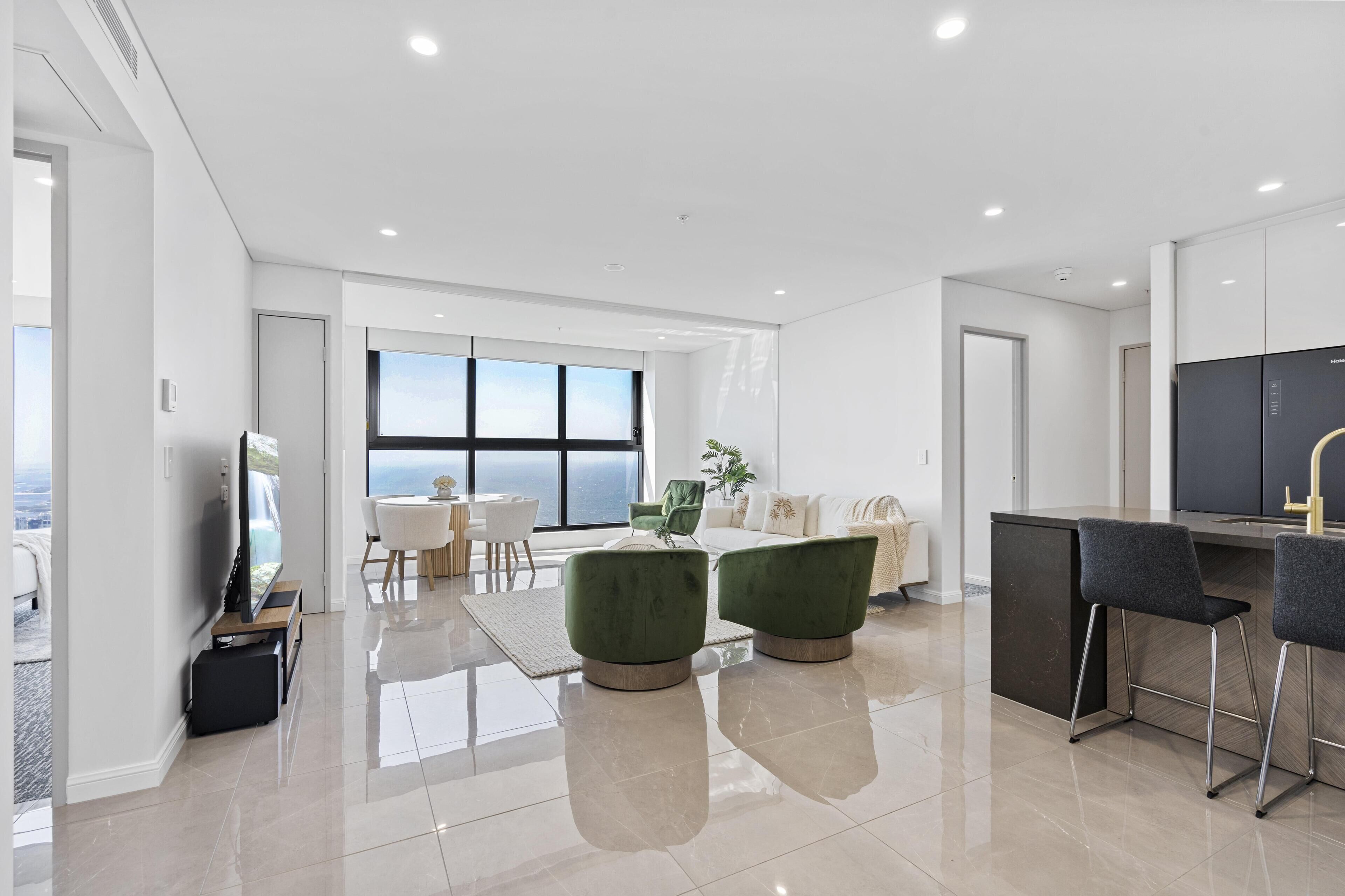 A modern living room with a large window, a sofa, a coffee table, and a TV.