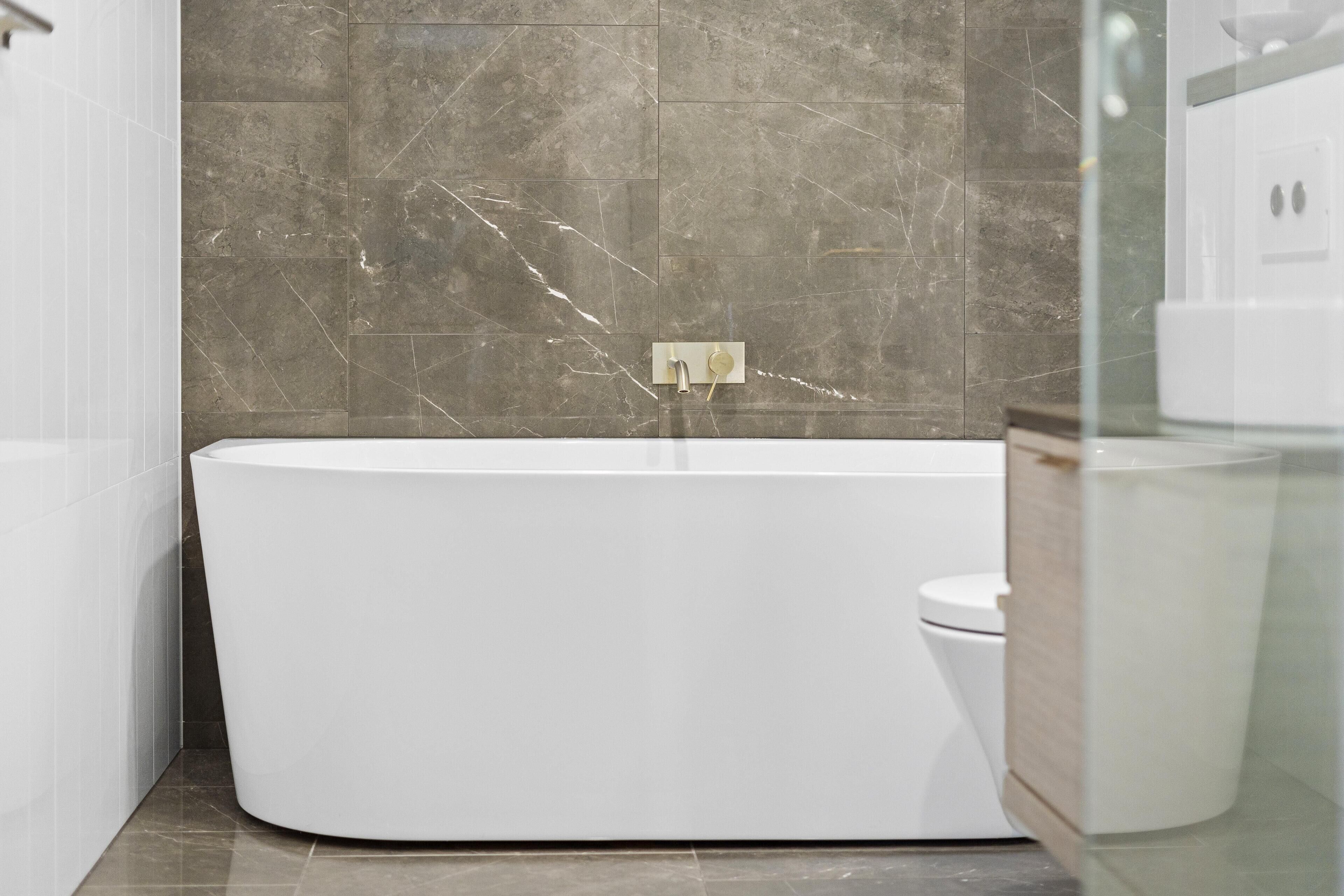 A modern bathroom with a freestanding bathtub, a toilet, and a glass shower enclosure.