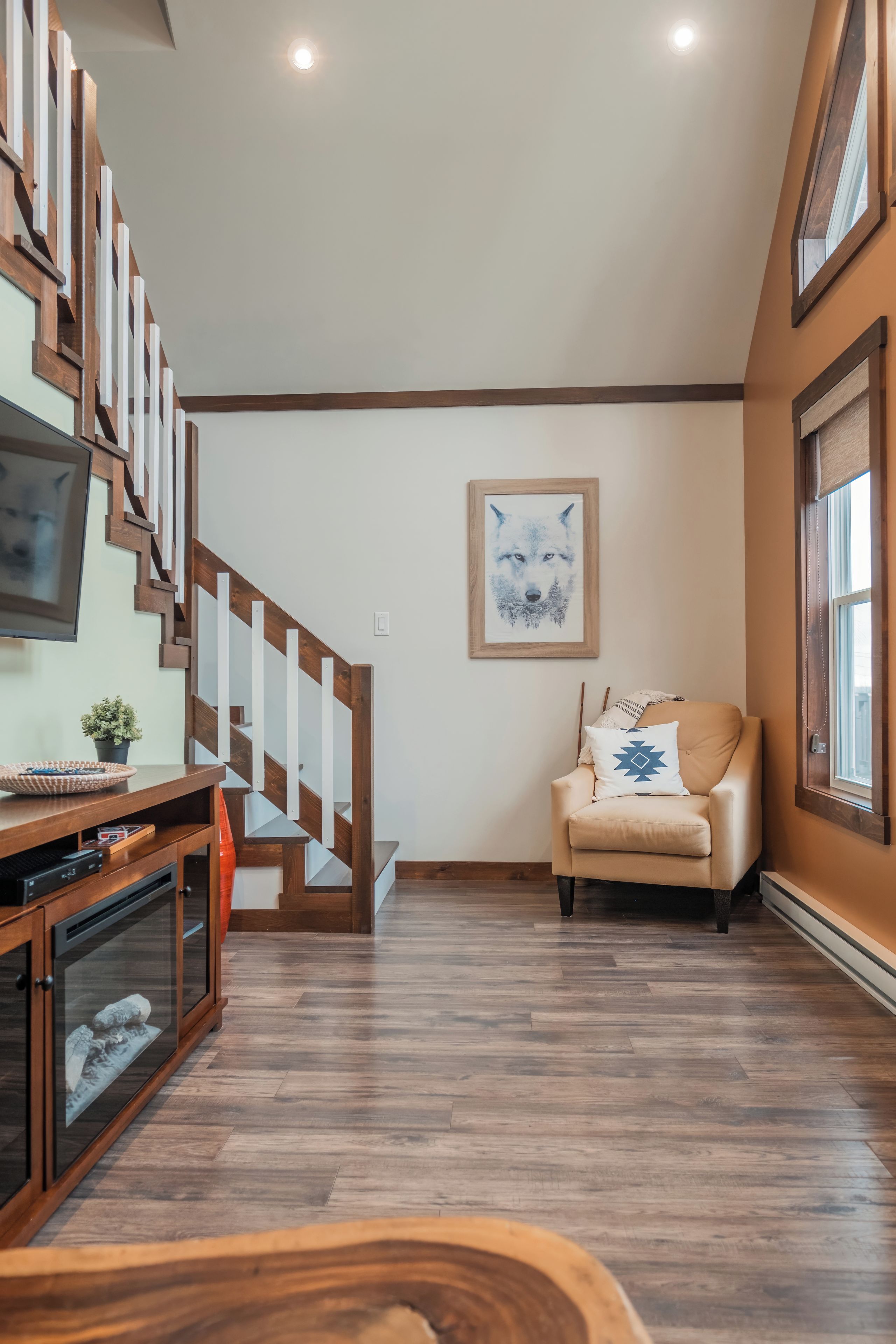 Un intérieur moderne avec un escalier en bois, un canapé et une œuvre d’art encadrée au mur.