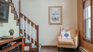 Un intérieur moderne avec un escalier en bois, un canapé et une œuvre d’art encadrée au mur.