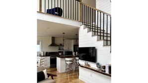 A modern kitchen with white cabinetry, a central island, and a dining area with bar stools.