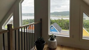 A room with large windows offering a view of a body of water and distant hills.