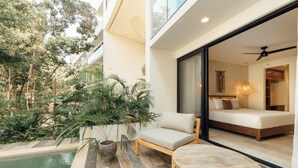 A modern hotel room with a balcony, a pool, and a view of the surrounding greenery. - 101 Park Tulum by Lumina (Tulum)