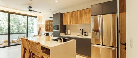 Una cocina moderna con una isla grande, electrodomésticos de acero inoxidable y vistas al exterior.