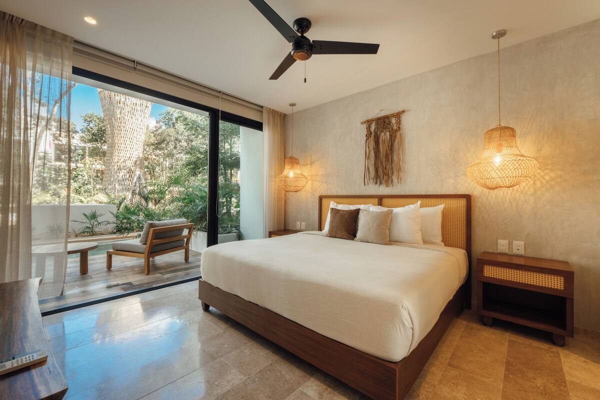 A spacious bedroom with a large bed, a ceiling fan, and a view of the outdoors.