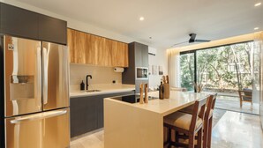 A modern kitchen with a central island, stainless steel appliances, and a view of the outdoors. - 101 Park Tulum by Lumina (Tulum)
