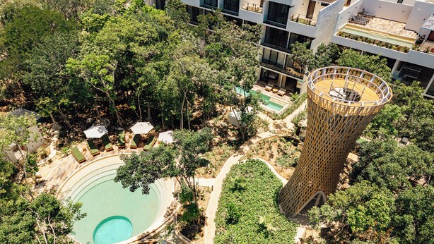 An aerial view of a modern resort with a swimming pool, lounge areas, and a unique tower structure. - 101 Park Tulum by Lumina (Tulum)