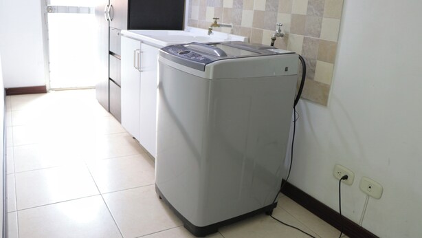 Une petite buanderie équipée d’un lave-linge, d’un évier et d’un pare-feu en carrelage.