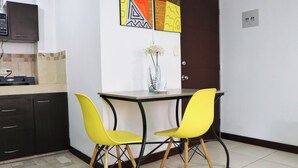 Une petite cuisine avec une table à manger et deux chaises jaunes, un vase avec des fleurs et un buffet.