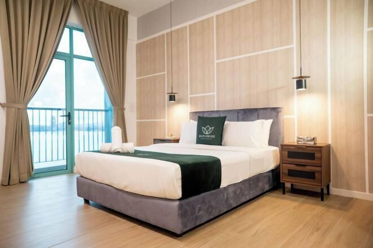 Une chambre d’hôtel avec un grand lit, une table de chevet, une commode et une vue sur l’extérieur grâce à une porte vitrée.