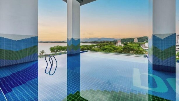 Una piscina infinita con vistas despejadas del paisaje, que incluyen colinas y una masa de agua.