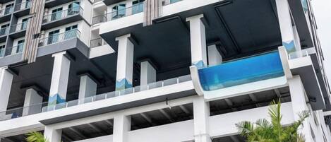 A multi-story building with balconies and a blue water feature.