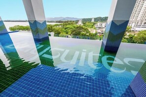 Una piscina con vistas a un paisaje urbano y montañas al fondo.