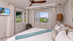 Une chambre spacieuse avec un grand lit, un ventilateur de plafond et une vue sur l’extérieur.