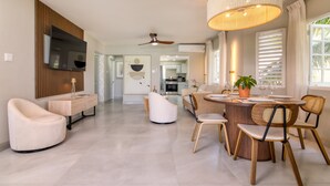 Un salon moderne comprenant un coin repas, un téléviseur fixé au mur et un ventilateur de plafond.