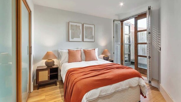 Een slaapkamer met een bed, twee nachtkastjes, een raam en een deur.
