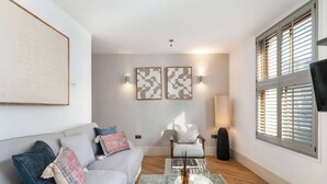 Een moderne woonkamer met een bank, fauteuils, een salontafel en kunstwerken aan de muren.