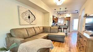 Een moderne woonkamer met een modulaire bank, een keuken op de achtergrond en een eethoek.