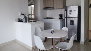 A modern kitchen with a central island, a dining table with chairs, and a refrigerator.