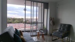 A modern living room with a grey sofa, a grey armchair, and a small table with a plant.