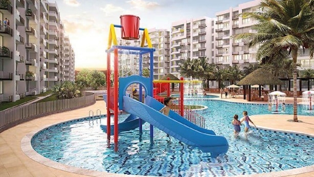 A swimming pool with a slide and play structure, surrounded by apartment buildings.