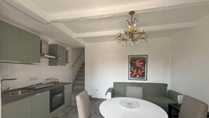 A modern kitchen with a dining area, featuring a chandelier, a staircase, and a framed artwork on the wall. - Sormano 1 - THE V Collection Apartment by OGS (Sormano)