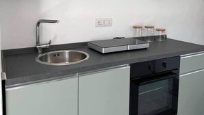 A modern kitchen with a stainless steel sink, a built-in oven, and a countertop with jars. - Sormano 1 - THE V Collection Apartment by OGS (Sormano)
