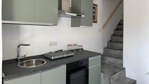A compact kitchen with a built-in oven, a sink, and a countertop with jars. - Sormano 1 - THE V Collection Apartment by OGS (Sormano)