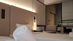 Ein Hotelzimmer mit zwei Betten, einem Schreibtisch, einem Stuhl und einem großen Spiegel.