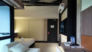 Ein Hotelzimmer mit Bett, einer Couch, einem Fernseher und einer Minibar.