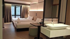 Ein Hotelzimmer mit einem großen Bett, einem Nachttisch, einem modernen Waschbecken und einem großen Spiegel.