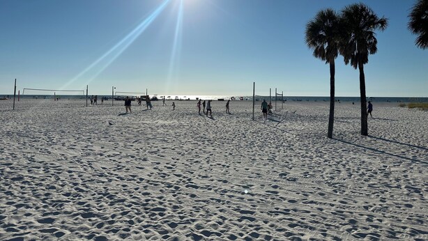 Una cancha de voleibol de playa con palmeras y cielo despejado.