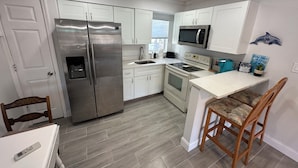 Una cocina moderna con armarios blancos, electrodomésticos de acero inoxidable y una mesa de comedor de madera con sillas.