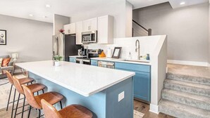 Une cuisine moderne avec un îlot central, des meubles blancs et des touches de couleur bleue.