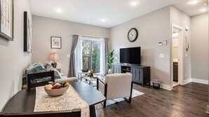 A living room with a dining table, a TV, and a window with curtains. - Trendy Townhouse in Midtown Omaha|Rooftop Retreat (Omaha)