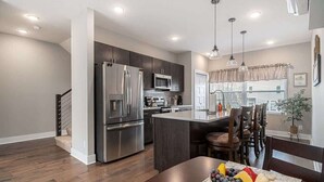 A modern kitchen with stainless steel appliances, a central island, and pendant lighting. - Trendy Townhouse in Midtown Omaha|Rooftop Retreat (Omaha)